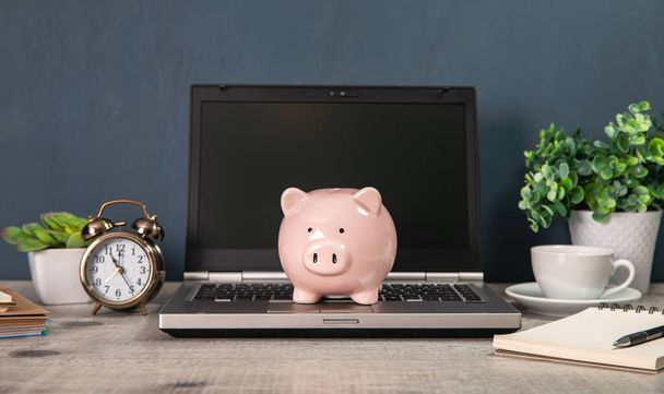 piggy bank on the notebook with clock on working tabl - Fotografie, Obrázek