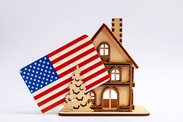 Symbolhaus aus Holz mit Schornstein und US-Flagge auf hellem Hintergrund. - Foto, Bild