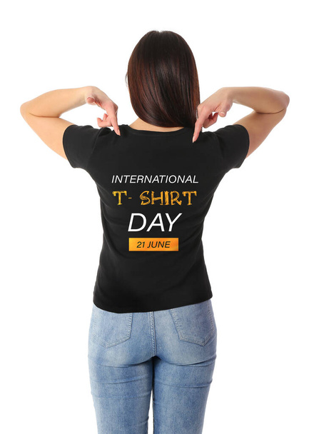 Νεαρή γυναίκα που δείχνει το μαύρο μπλουζάκι σε λευκό φόντο, πίσω όψη. Διεθνής Ημέρα T-shirt - Φωτογραφία, εικόνα