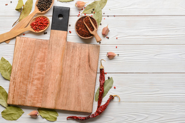 New cutting board and spices on light wooden background - Фото, изображение