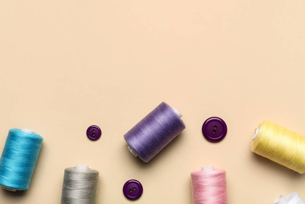 Sewing threads with buttons on beige background - Photo, Image