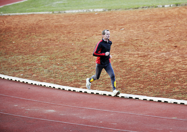 Adult man running on athletics track - Foto, afbeelding