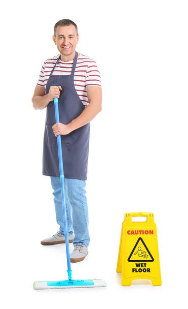 Trabajador maduro del servicio de limpieza con fregona y signo de precaución sobre fondo blanco - Foto, Imagen