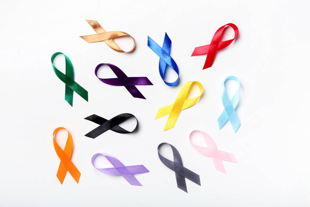 Different scattered awareness ribbons on white background. World Cancer Day concept - 写真・画像