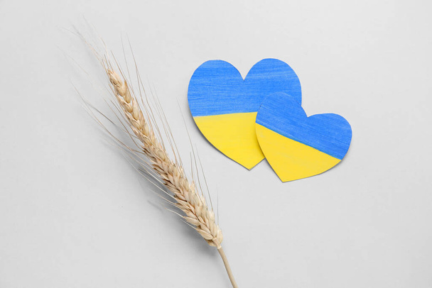 Χάρτινες καρδιές σε χρώματα της ουκρανικής σημαίας και spicelet σιταριού στο φως φόντο - Φωτογραφία, εικόνα