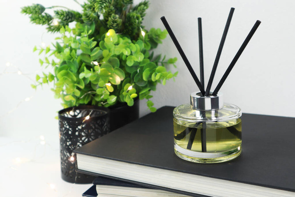 luxury aroma scent reed diffuser glass bottle is on white table with books to creat romantic and relax ambient in bedroom with white cement wall background in the morning for happy valentine day - 写真・画像