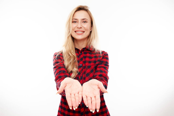 Attractive blonde girl promoter holding something in hand demonstrating empty space with excited face isolated on white background - Fotó, kép