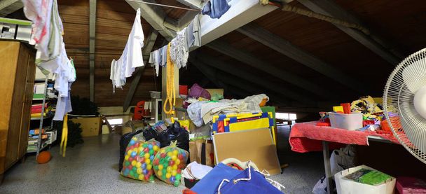 interior de um grande sótão de uma escola com velhos brinquedos de lixo e roupas penduradas - Foto, Imagem