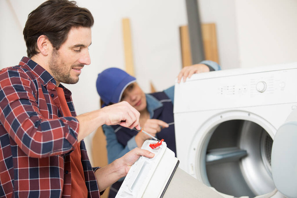man screws the cover of the washing machine - Фото, зображення
