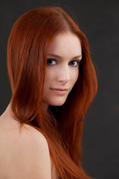 Güzelliği karanlığın içindeki bir ışık. Siyah bir arka planda duran kızıl saçlı güzel bir kadının portresi.. - Fotoğraf, Görsel