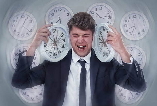 So many deadlines, so little time. A businessman screaming while surrounded by multiple clocks. - Foto, Imagen