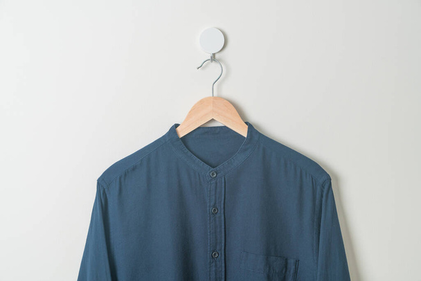 hanging navy shirt with wood hanger on wall - Zdjęcie, obraz