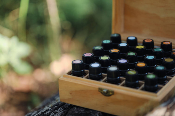 Ефірні пляшки з олією в дерев'яній коробці для зберігання з яскравими наклейками кришки в природній зовнішній обстановці
 - Фото, зображення