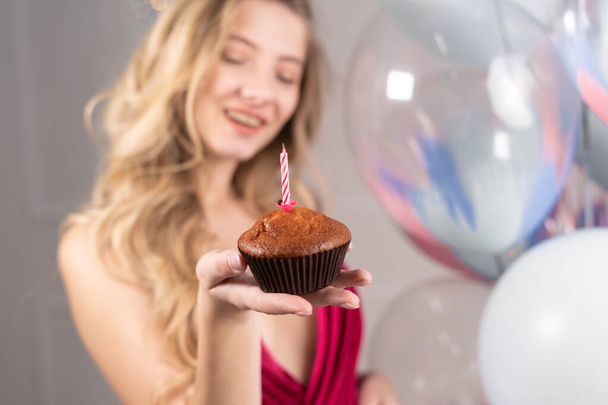 Close-up weibliche Hand hält Cupcake mit Kerzen Geburtstagsfeier Konzept. Kopierraum. - Foto, Bild
