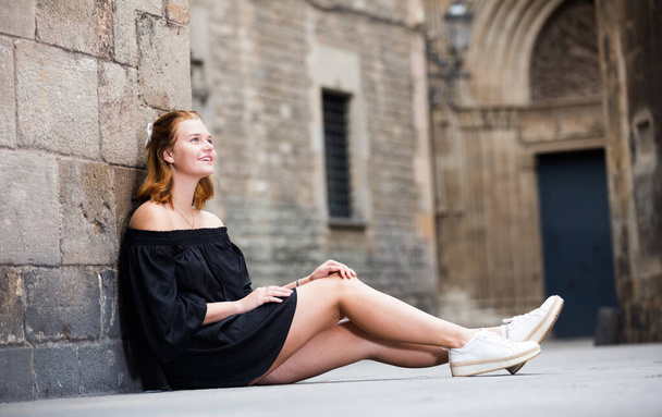 smiling female sitting near the stone wall - Fotografie, Obrázek