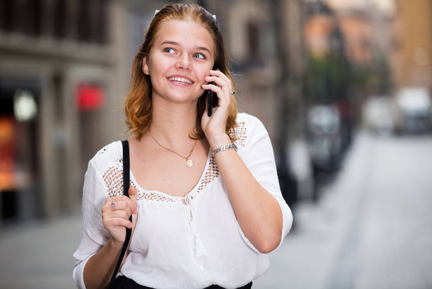 Portrait of smiling girl teenager talking on phone - Photo, Image