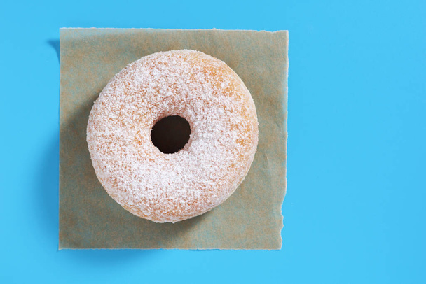 Bovenaanzicht van klassieke donut met poedersuiker, op een blauwe achtergrond, met kopieerruimte - Foto, afbeelding