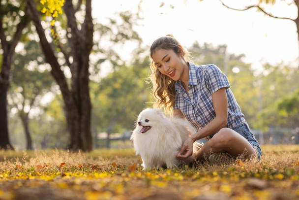 Mujer feliz abrazando lindo cachorro blanco en verano en la luz del atardecer. Auténtico momento hermoso. Chica con estilo relajarse con su adorable cachorro en un picnic. Amigo leal.. - Foto, imagen