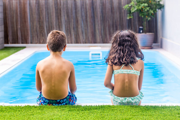 Two little kids on the edge of the swimming pool. Rear view - Foto, imagen