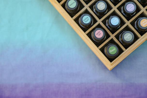 Вид зверху вниз на ефірні пляшки з олією в дерев'яній коробці для зберігання з яскравими барвистими наклейками кришки
 - Фото, зображення