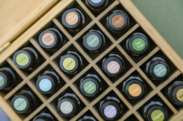 Top-down άποψη των μπουκαλιών αιθέριο έλαιο σε ξύλινο κουτί αποθήκευσης με φωτεινά πολύχρωμα αυτοκόλλητα καπάκι - Φωτογραφία, εικόνα