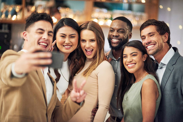 Szybkie selfie, póki zabawa trwa. Przycięte zdjęcie grupy młodych przyjaciół pozujących razem do selfie w barze. - Zdjęcie, obraz