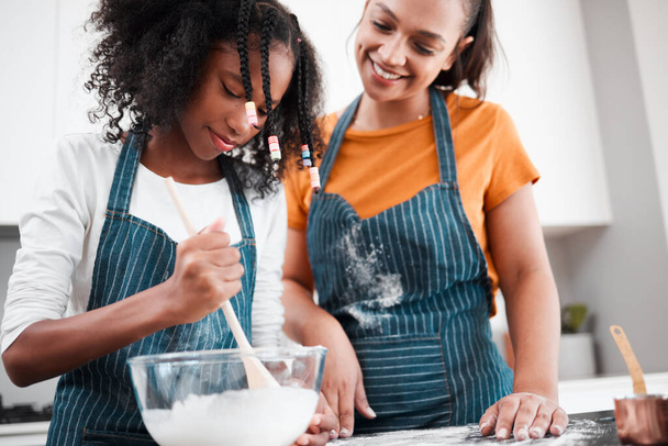 Mix it all together. Shot of a mother and daughter baking together in the kitchen at home. - Фото, изображение