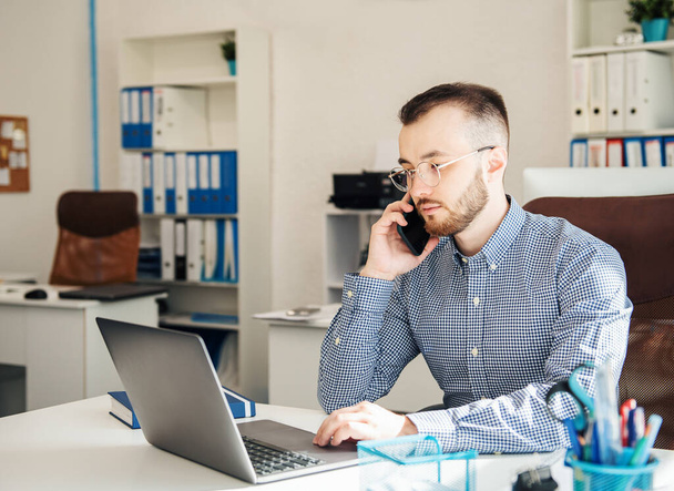 Joven Empresario con camisa trabajando en su portátil en una oficina - Foto, imagen