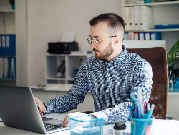 Joven Empresario con camisa trabajando en su portátil en una oficina - Foto, Imagen