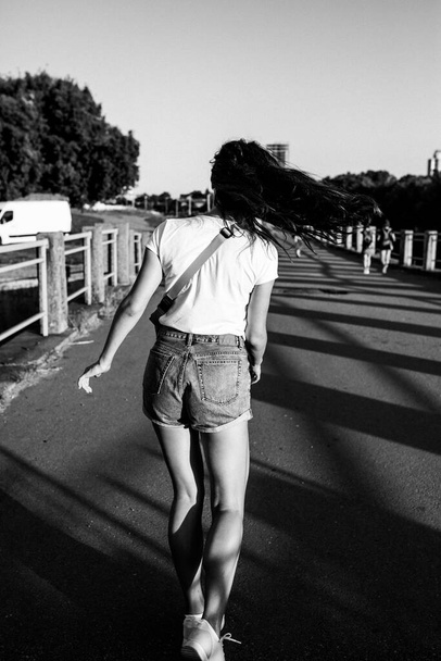 a girl in shorts and a T-shirt in the summer running along the promenade - Foto, Bild