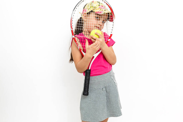 Nettes kleines Mädchen mit Tennisschläger in den Händen auf weißem Hintergrund - Foto, Bild