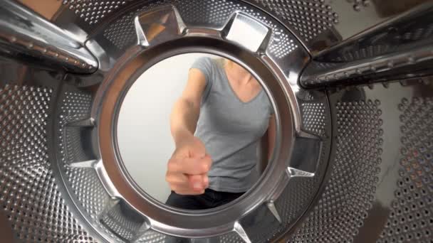 chamber is inside drum of washing machine. woman's hand shows fig and an obscene gesture, fuck you. woman puts her hand inside and shows that she is tired of doing laundry and cleaning. wants to rest - Imágenes, Vídeo