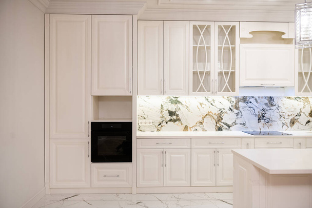 Doğal ahşaptan yapılmış, ev aletleri ve ışıklandırmayla döşenmiş beyaz bir mutfak. - Fotoğraf, Görsel