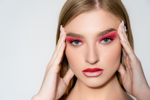 Young woman with red makeup looking at camera isolated on grey  - Foto, immagini