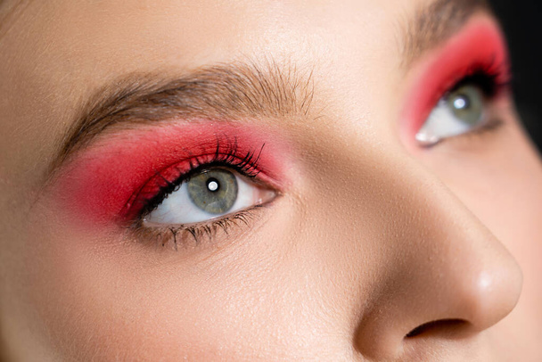 Cropped view of woman with red eye shadow looking away isolated on black  - Foto, Imagem