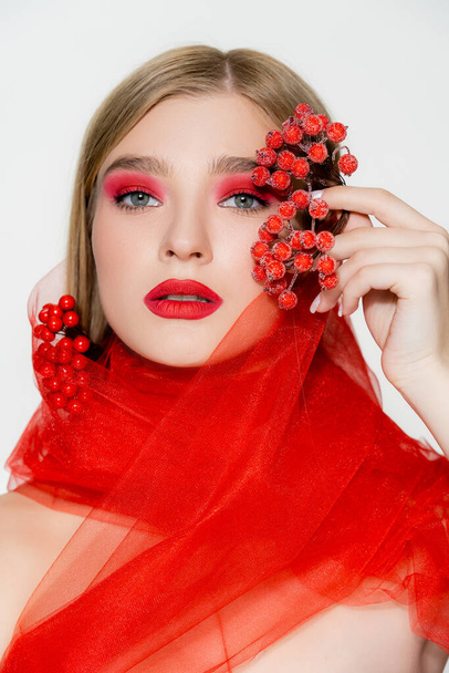 Model with makeup and red cloth holding berries isolated on white - Foto, afbeelding