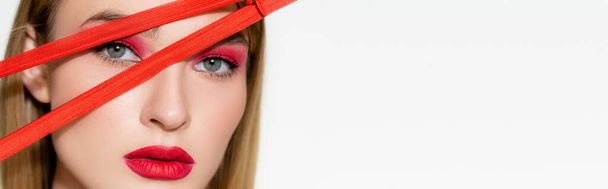 Kırmızı göz farı ve dudakları olan genç bir model fermuarın yakınındaki kameraya bakıyor beyaz pankartta izole edilmiş.  - Fotoğraf, Görsel