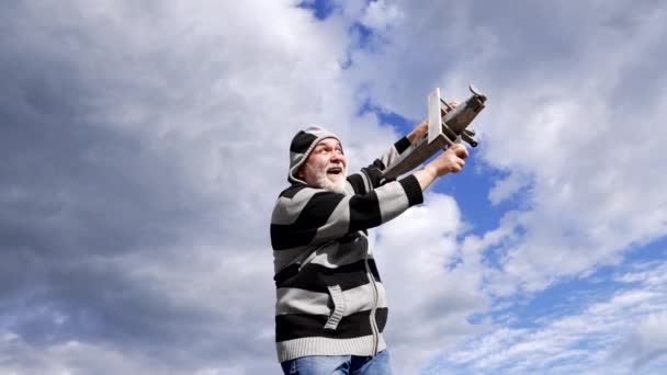 Glücklicher älterer Mann täuscht vor, mit Modellflugzeug in den Himmel zu fliegen - Filmmaterial, Video