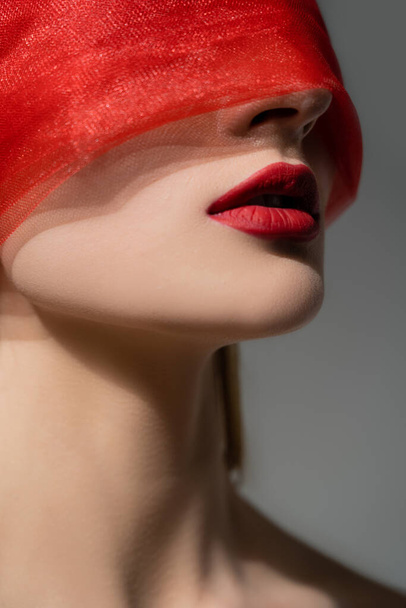 Woman with red lips and cloth on face posing isolated on grey  - Foto, Imagem