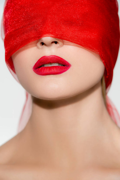 Mladá žena s červenými rty a tkaninou na obličeji izolované na šedé  - Fotografie, Obrázek