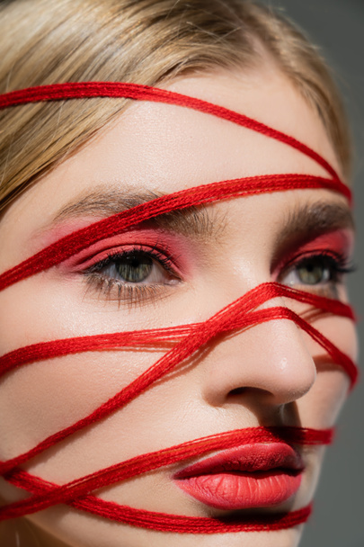 Close up view of red threads on face of woman with makeup isolated on grey  - Fotografie, Obrázek
