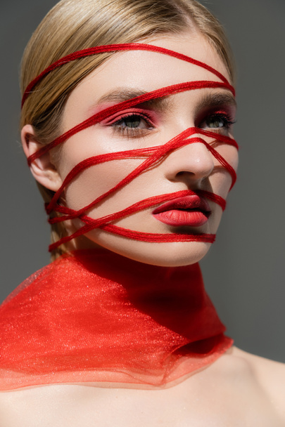 Fair haired model with red threads and visage looking away isolated on grey  - Foto, immagini
