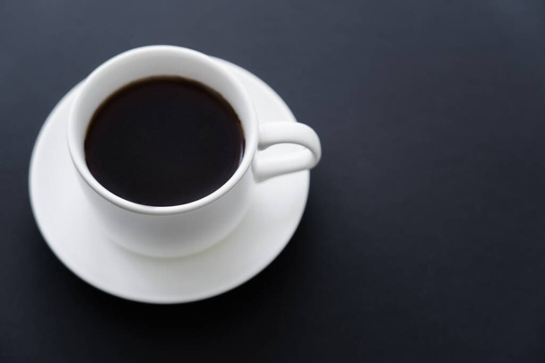 πάνω όψη αρωματικού φλιτζανιού καφέ με πιατάκι σε μαύρο  - Φωτογραφία, εικόνα