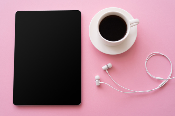 top view of digital tablet with blank screen near cup of coffee and wired earphones on pink  - Foto, Imagen