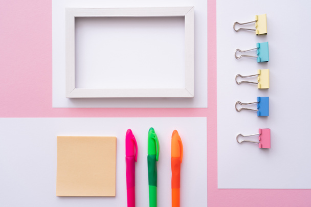 flat lay of colorful stationery near blank frame and papers on pink - Фото, изображение