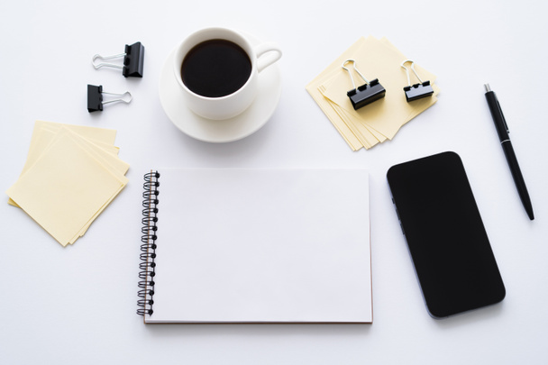 top view of smartphone with blank screen near cup of coffee and stationery on white - Fotografie, Obrázek