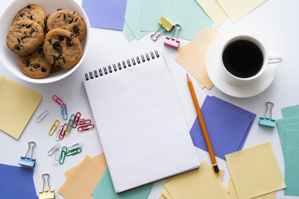 top view of bowl with biscuits near cup of coffee and stationery on white - Photo, Image
