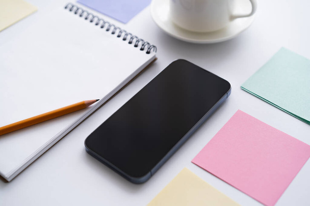 close up of stationery near smartphone with blank screen on white - Foto, Bild