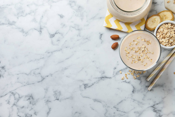 Glass of tasty banana smoothie with oatmeal on white marble table, flat lay. Space for text - Foto, Imagem