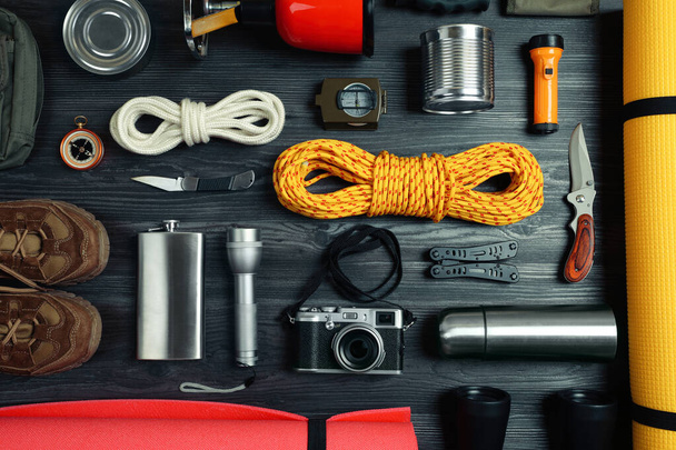 Flat lay composition with different camping equipment on dark wooden background. Traveler set - Foto, imagen